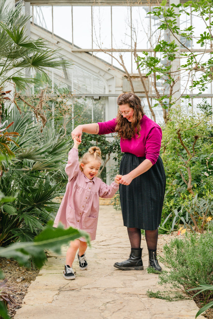 Dansende mama en dochter tijdens een gezinsfotoshoot in de plantentuin van Meise